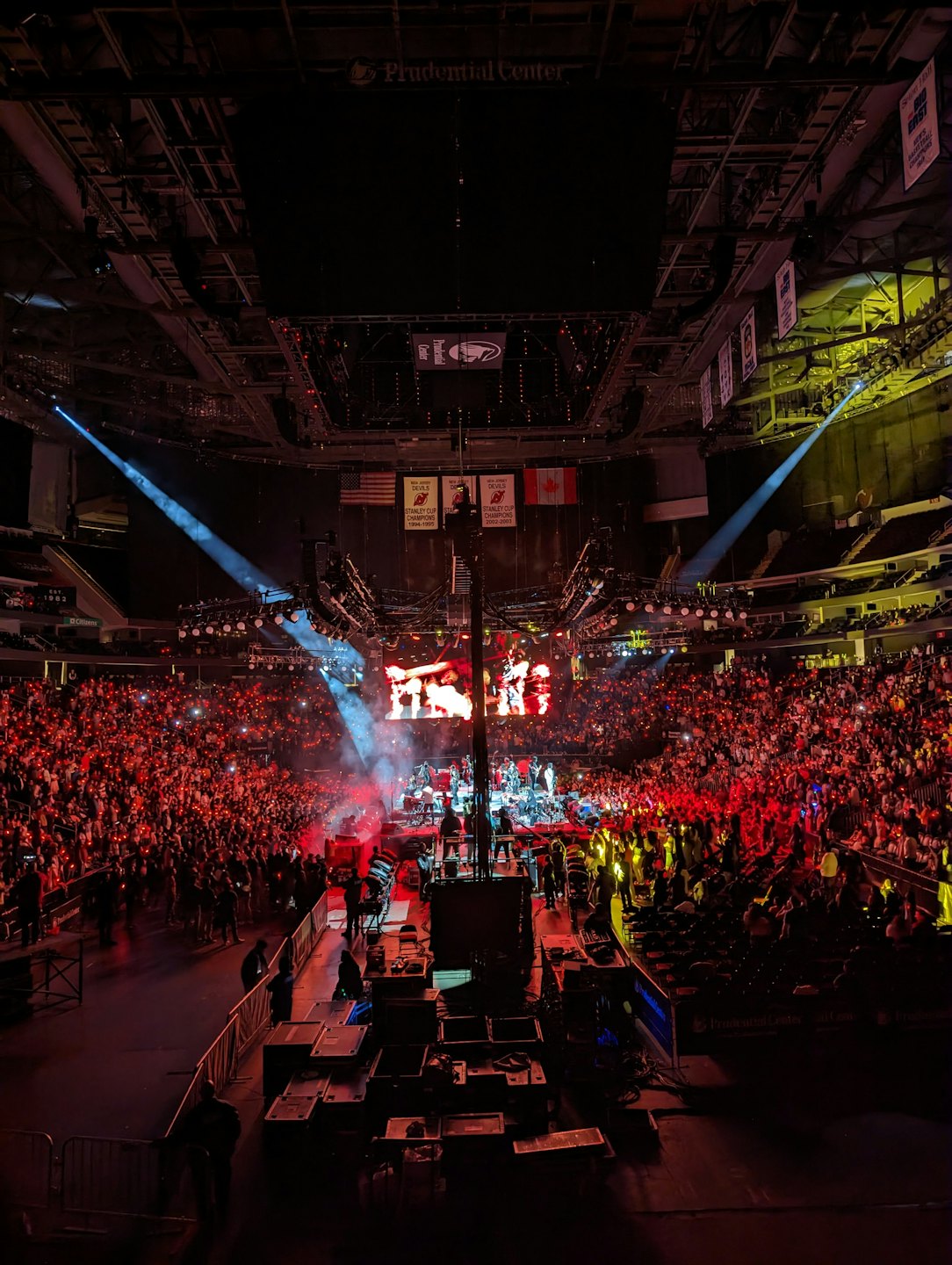 Crowd holding illuminated lights at a concert in an arena.