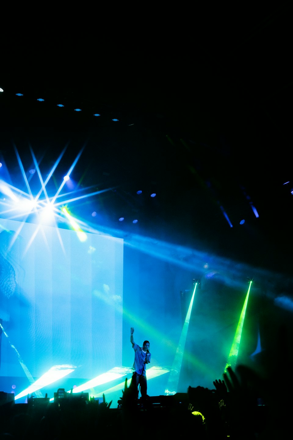 Male singer performs on stage under blue and green lights.