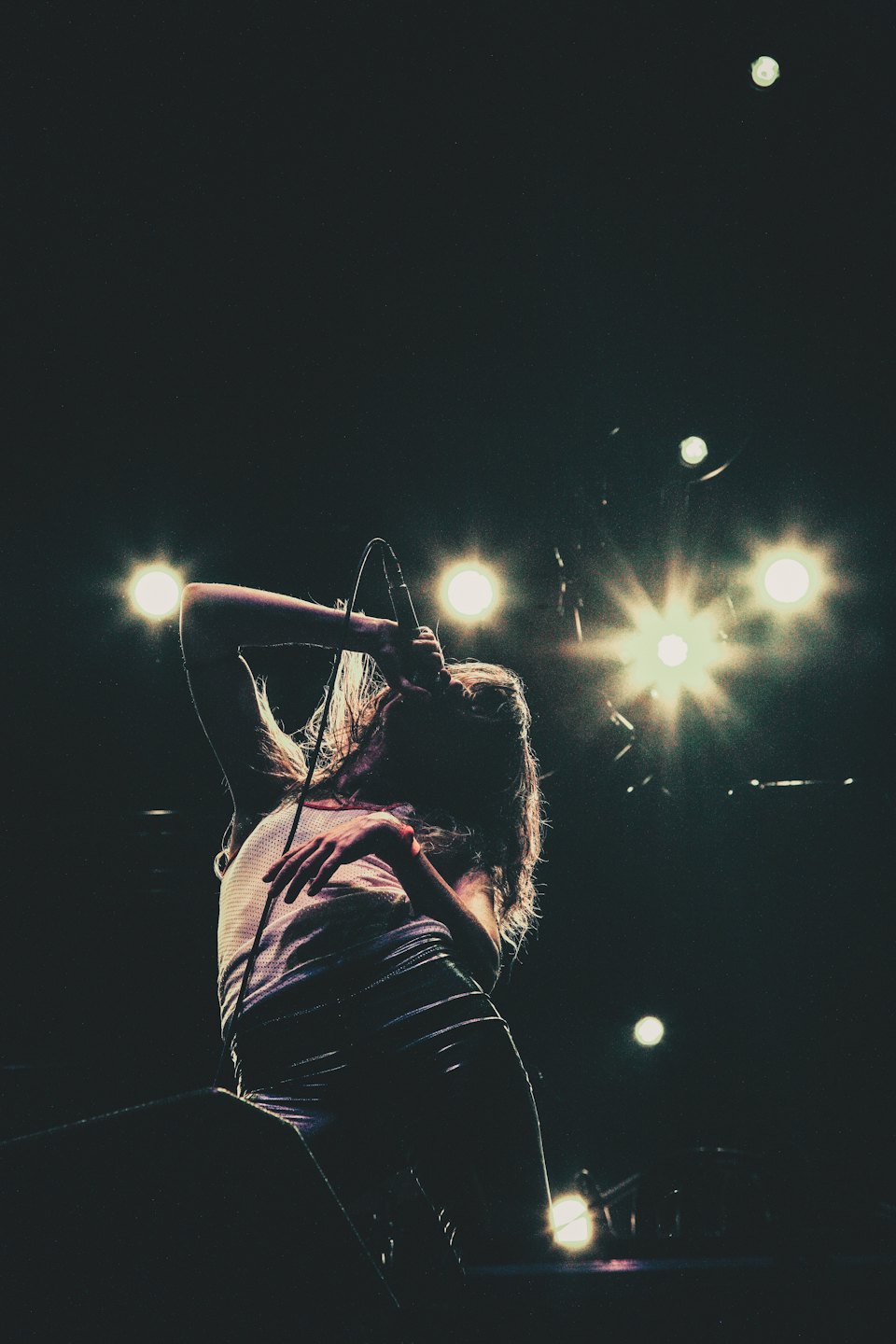 Female singer belts out a song on stage with raised arm.
