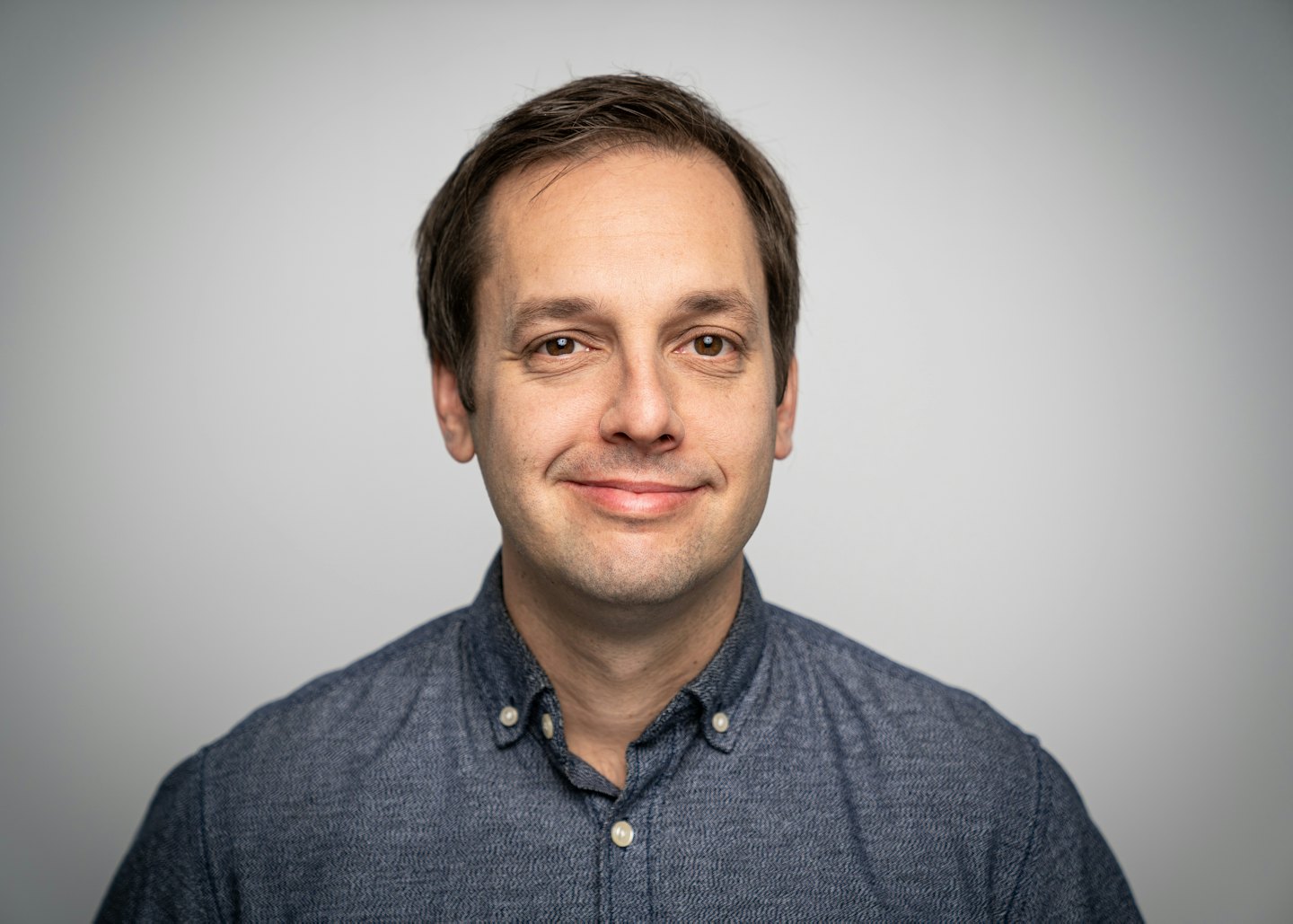 Smiling man in a blue shirt for a professional portrait.
