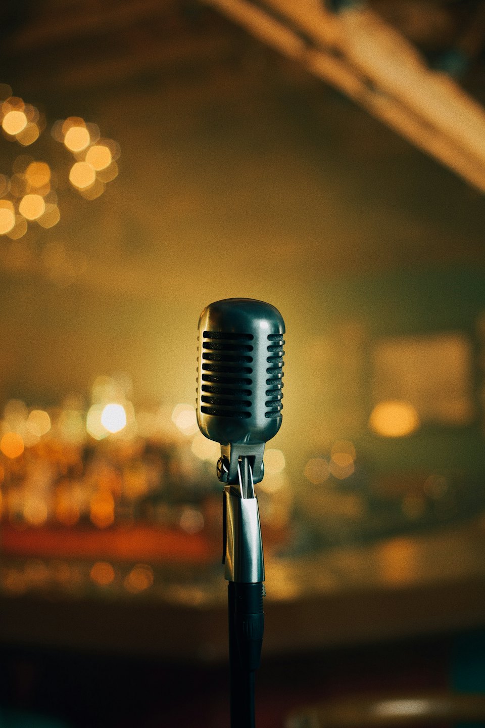 Vintage microphone stands on a softly lit stage.